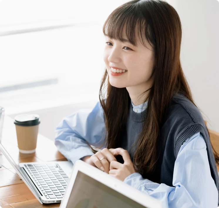 デスクでパソコンを前に、リラックスした表情で話を聞く女性社員のカット