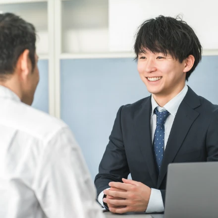 面談や対面相談ブースで、顧客の話を笑顔で親身に聞くスーツ姿 vacuum の若い男性社員