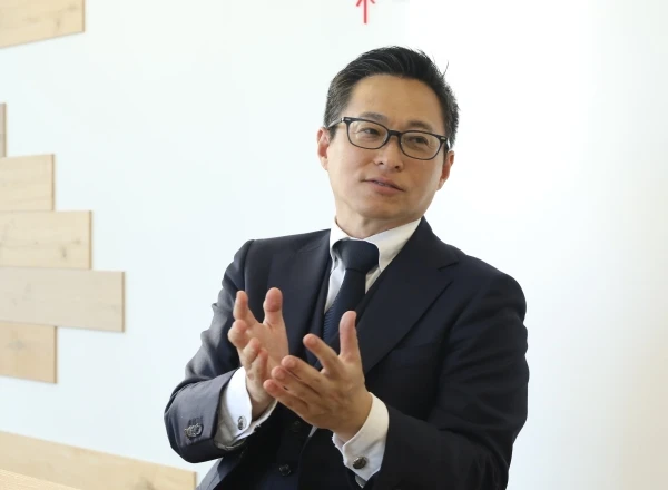 身振り手振りを交えながら、真剣な表情で打ち合わせや説明をするメガネの男性ビジネスマン