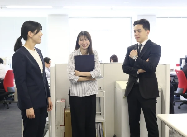 オフィスの執務室で、和やかな雰囲気で談笑する3人のビジネスパーソン