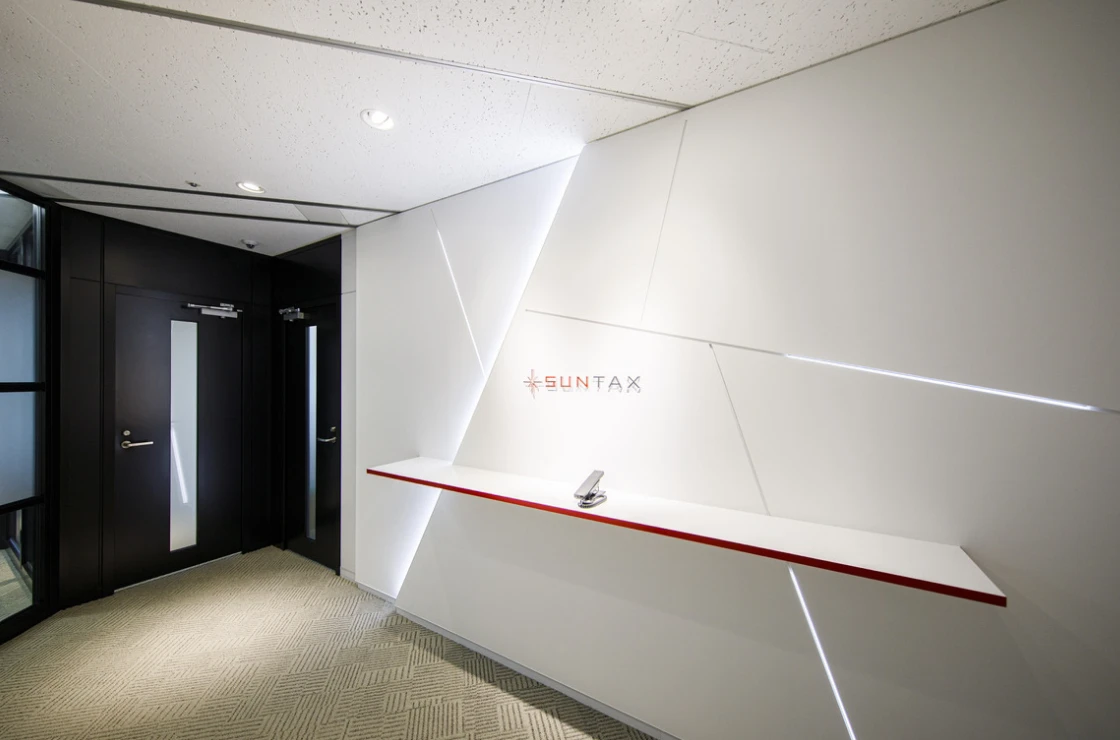 白を基調としたシャープなデザインと赤いラインが特徴的な、SUNTAXオフィスの受付・エントランス