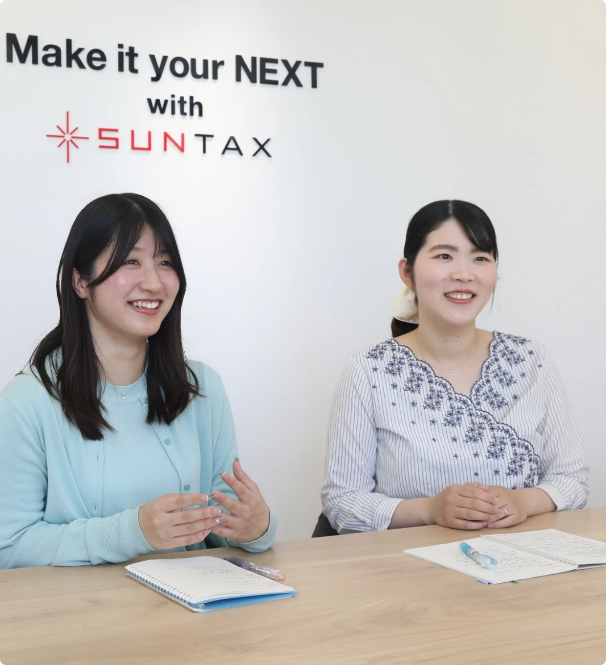 打ち合わせスペースで、身振り手振りを交えながら笑顔で意見を交わす女性社員たち